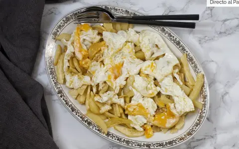 Plato de patatas fritas cubiertas con huevos rotos, con las yemas aún líquidas. Un clásico reconfortante.