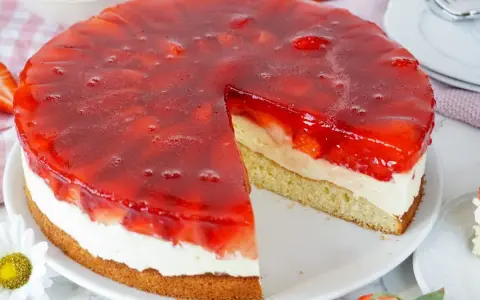 Ein saftiger Erdbeerkuchen mit Pudding, Sahne und einer glänzenden Erdbeer-Gelee-Schicht. Ein Stück fehlt bereits.