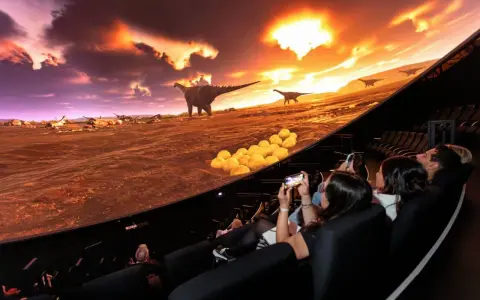 Besökare njuter av en dinosaurieupplevelse i en kupolformad salong, som en del av universum i Göteborg.