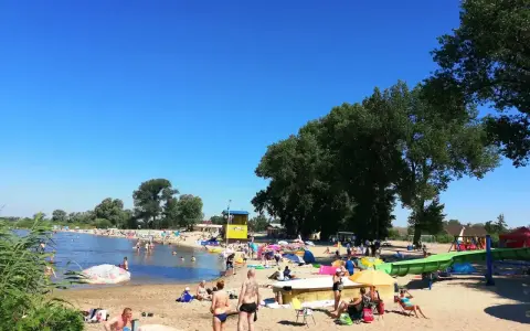 Słoneczny dzień na plaży, ludzie odpoczywają nad wodą. Zastanawiasz się, ile kilometrów jest ze Szczecina nad morze? To idealne miejsce na relaks przed podróżą.