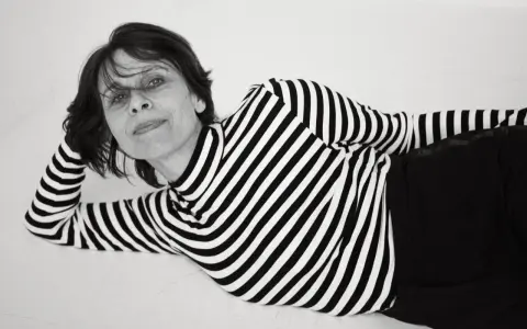 Katarzyna Krzanowska w czarno-białym swetrze w paski, leżąca na boku, z ręką pod głową.