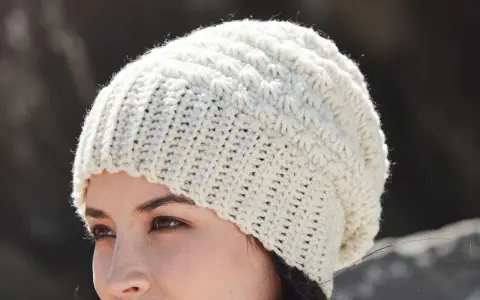 Mujer con gorro de ganchillo blanco con patrón texturizado. ¡Encuentra gorros de ganchillo patrones gratis para crear el tuyo!
