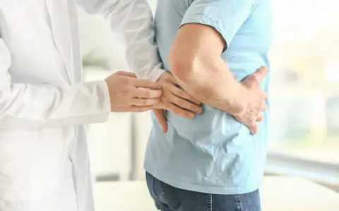 Lekarz bada pacjenta z bólem w boku, sugerującym rozbijanie kamieni nerkowych.