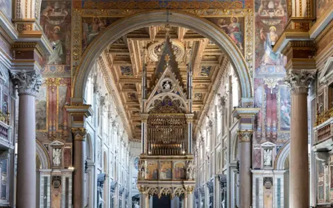 Interno di San Giovanni in Laterano: maestoso baldacchino, affreschi dorati e colonne imponenti creano un'atmosfera sacra.