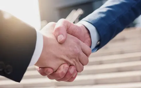 Umorzenie postępowania egzekucyjnego zakończone uściskiem dłoni. Dwie osoby w garniturach potwierdzają porozumienie.