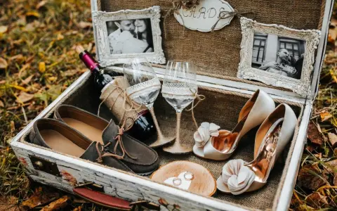 Elegancki prezent na ślub cywilny bez wesela: buty, wino, kieliszki, obrączki i zdjęcia pary w ozdobnej skrzyni.