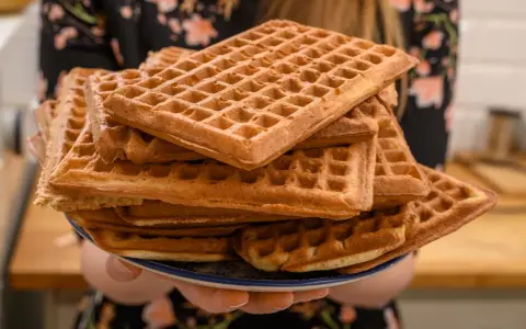 Une assiette débordante de gaufres dorées, parfaites pour une recette de gaufres croustillantes et moelleuses. Un délice à partager !