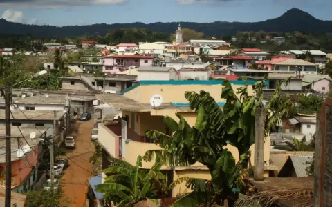 Vue d'une ville aux Comores, Mayotte, avec des maisons colorées, des bananiers et une montagne en arrière-plan.
