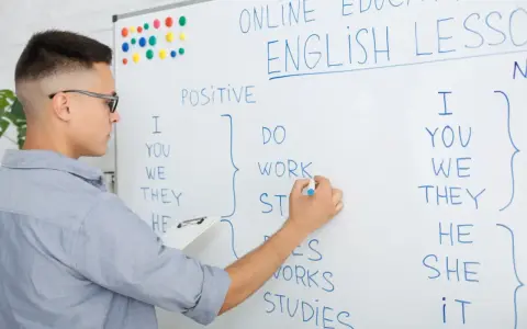 Chłopak pisze na tablicy "English Lesson". To materiał na blog język angielski o gramatyce.