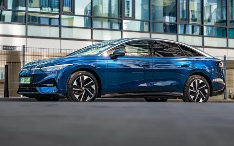 Niebieski Volkswagen ID.7 zaparkowany przed nowoczesnym budynkiem.