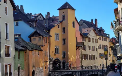 Magnifique journée pour visiter Annecy à pied. Les maisons colorées bordent le canal, un pont de pierre relie les rives.