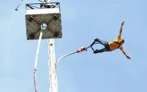 Mężczyzna w żółtej koszulce skacze na bungee. Zastanawiasz się, ile kosztuje skok na bungee?