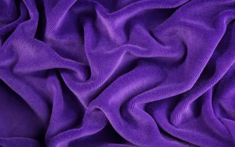 Tessuto di velluto viola drappeggiato, morbido e lussuoso. Scopri come lavare il velluto per mantenerlo splendente.