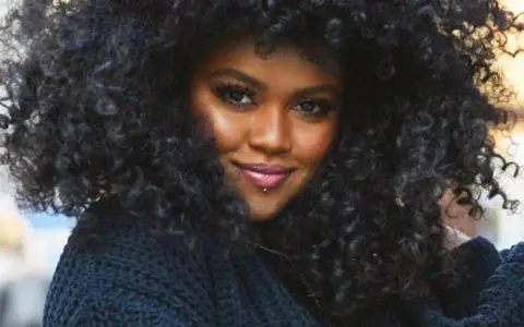 A woman with voluminous, natural curly hair, showcasing beautiful hairstyles for natural curly hair.