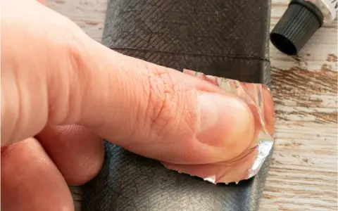 Palec dociska łatkę do dętki rowerowej, pokazując, jak wymienić dętkę w rowerze.
