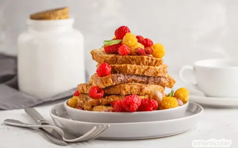 Gestapelte Scheiben Brot, garniert mit Himbeeren und gelben Beeren, perfekt zum Backen mit Hafermilch.