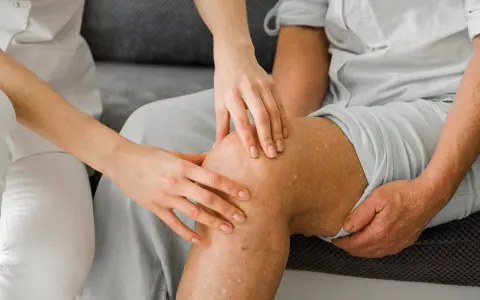 Fizjoterapeuta bada kolano pacjenta po usunięciu łąkotki, przygotowując go do powrotu do sportu.