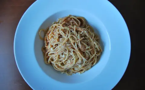 Spaghetti Napoli z sosem pomidorowym i parmezanem, podane w białej głębokiej misce.