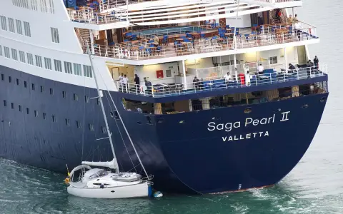 La nave da crociera "Saga Pearl II" è imponente accanto a una piccola barca a vela, mostrando la differenza tra nave e traghetto.