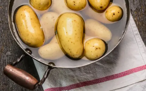 Kleine, gelbe Kartoffeln liegen in Wasser in einem Topf. Sie sind bereit, um sie zu kochen.