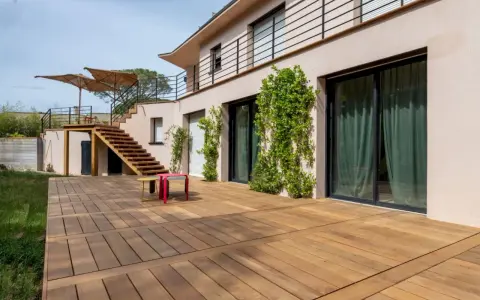 Grande terrasse en bois, une dalle terrasse directement sur terre, menant à un escalier extérieur.