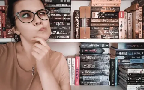 Dziewczyna z okularami zastanawia się nad wyborem książki. Na półkach obok kryminały, fantasy i erotyka subtelna.