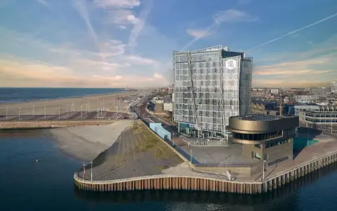 Modernes Hotel am Meer mit Glasfassade, Strand und Hafen.