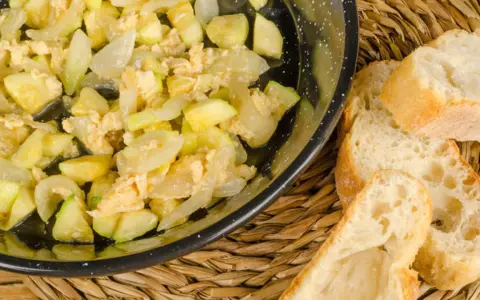 Zarangollo murciano, un revuelto de calabacín y cebolla, servido en sartén con pan rústico.