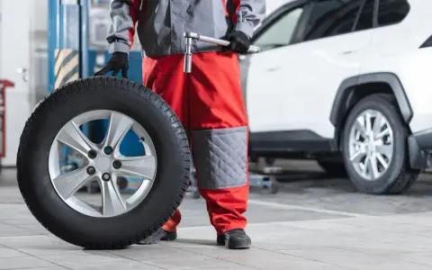 Mecánico con una rueda motriz de coche lista para ser instalada.
