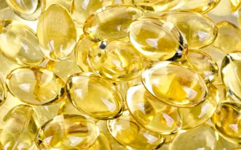 En hög med genomskinliga, gulaktiga kapslar som liknar solens strålar. Dessa kan vara vitaminer som ger energi.