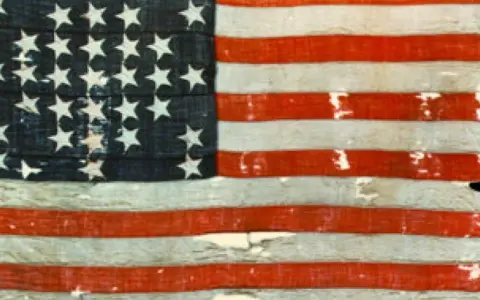 Pierwsza flaga USA, zniszczona i wyblakła, z 13 gwiazdami i pasami, świadectwo historii.