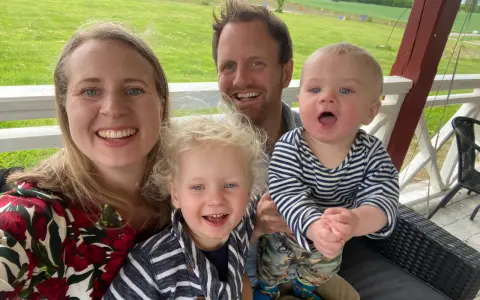 Familj med barn på en altan med grönskande landskap i bakgrunden. En härlig stund med norge med barn.