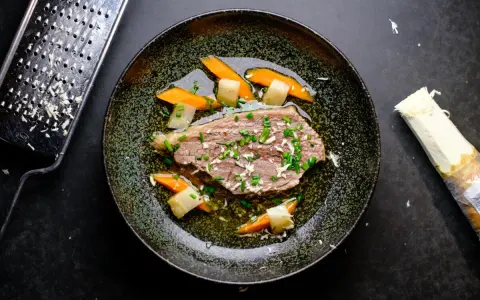Zarter Tafelspitz braten im Topf, serviert mit Karotten und Lauch. Frisch geriebener Meerrettich daneben.