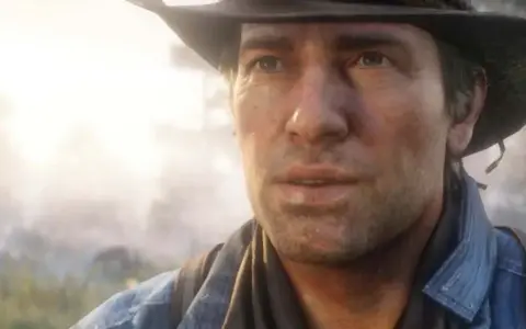 Arthur Morgan w kapeluszu i dżinsowej koszuli, zamyślony, na tle mglistego krajobrazu.