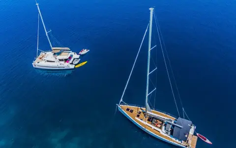 Zwei Segelboote, ein Katamaran und eine Yacht, liegen friedlich auf dem tiefblauen Meer.