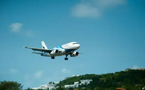 Samolot pasażerski z niebieskimi pasami na tle błękitnego nieba. Może to być przypomnienie o możliwości zwrotu biletu Ryanair zwrot biletu 24h.