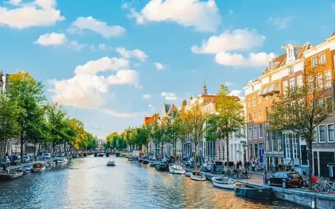 Widok na kanał w Amsterdamie, z łodziami, kamienicami i zielenią. Idealne miejsce, by poczuć, gdzie jest Amsterdam.