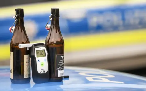 Zwei Bierflaschen und ein Alkoholtester auf einem Polizeiauto. Der Tester zeigt 0.00, aber die Gefahr einer 1 1 Promille Strafe bleibt.