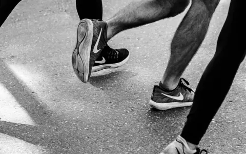 Gambe di corridori in azione, con particolare attenzione al consumo delle scarpe sportive Nike.