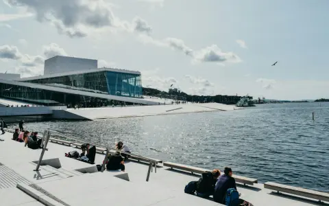 Oslo fiordy jak dojechać: nowoczesna Opera Narodowa i ludzie odpoczywający nad wodą.