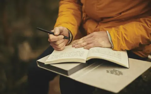 Mani che scrivono su un quaderno aperto, ispirate dalle riviste letterarie italiane.