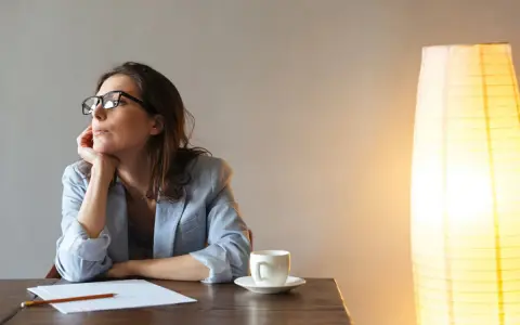 Kobieta w okularach, z podpartą dłonią brodą, pogrążona w myślach. Jej neurotyzm zdaje się być odzwierciedlony w zamyślonym spojrzeniu.