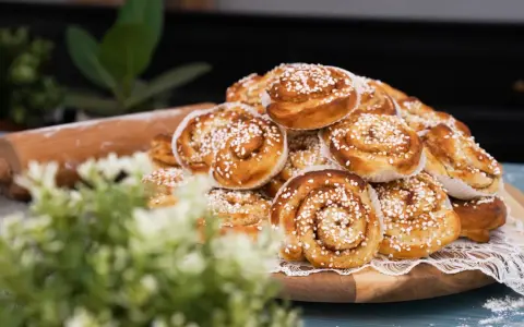 En hög med gyllene kanelbullar, redo att bakas enligt ett enkelt kanelbullar recept. En kavel ligger bredvid.