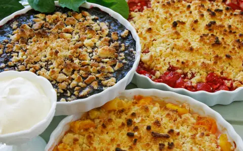 Tre ugnsbakade smulpajer med blåbär, jordgubbar och persika. Perfekt för ett smuldeg recept. Serveras med en klick grädde.