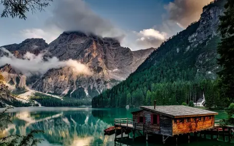 Lago alpino con baita in legno e montagne nebbiose. Curiosità sul Trentino Alto Adige: un luogo da fiaba.