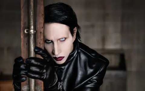 Marilyn Manson w Warszawie, w czarnej skórzanej kurtce i rękawiczkach, z charakterystycznym makijażem.