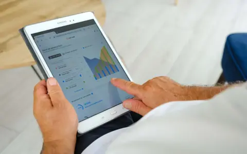 Homme consultant sa tablette : suivi de production solaire, consommation, autoconsommation et injection gratuite ENEDIS.