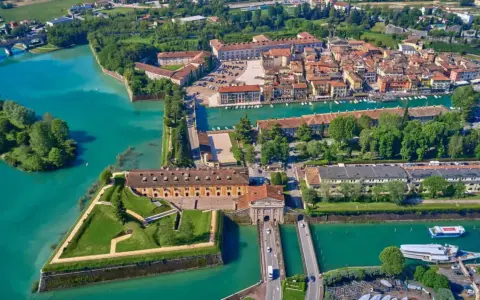 Peschiera del Garda centro storico: fortezza a stella circondata da acque turchesi, con edifici storici e un ponte.