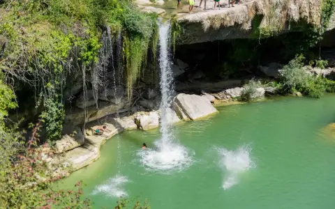 Disfrutando del baño en piscinas naturales junto a la cascada de Tobera. Un grupo de amigos se lanza al agua turquesa.