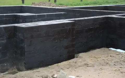 Fundament betonowy z czarnym abizolem, gotowy na kolejne etapy budowy.